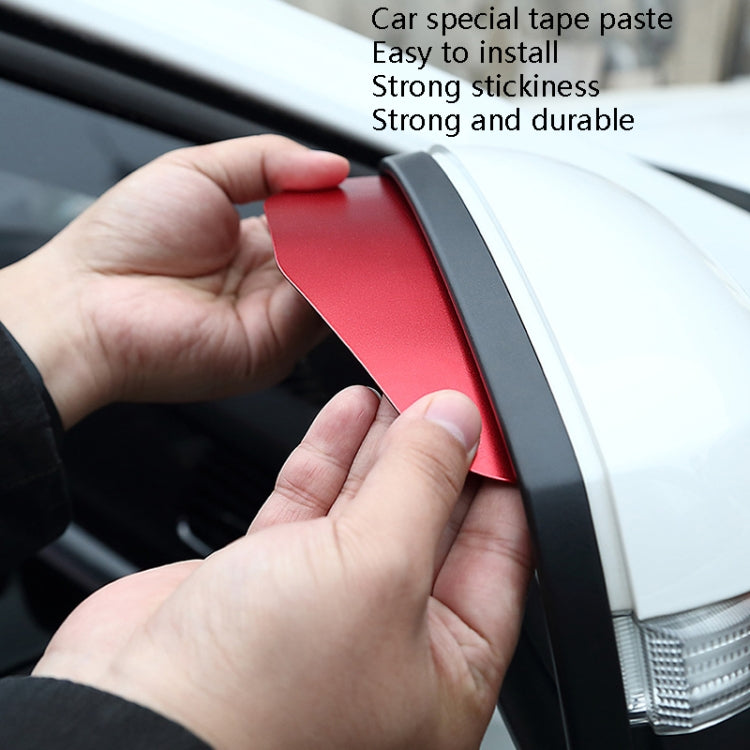 Hands applying a red car rear view mirror rain shield cover to a side mirror