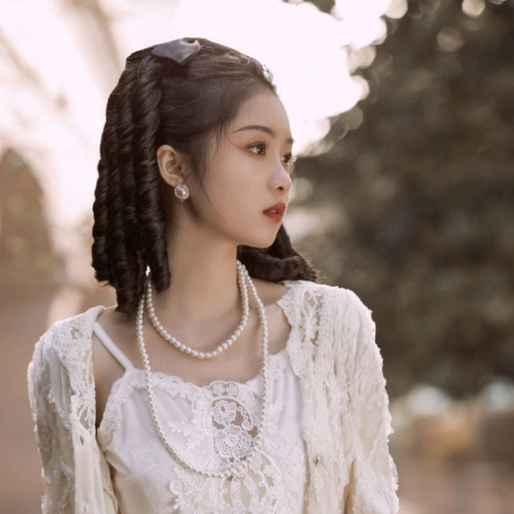 Black curly ponytail wig with satin bow worn to the side, voluminous curls visible
