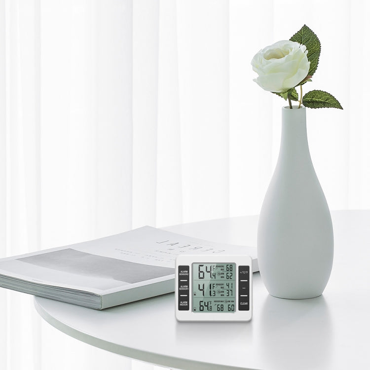 White digital thermometer resting on table with LCD temperature readings
