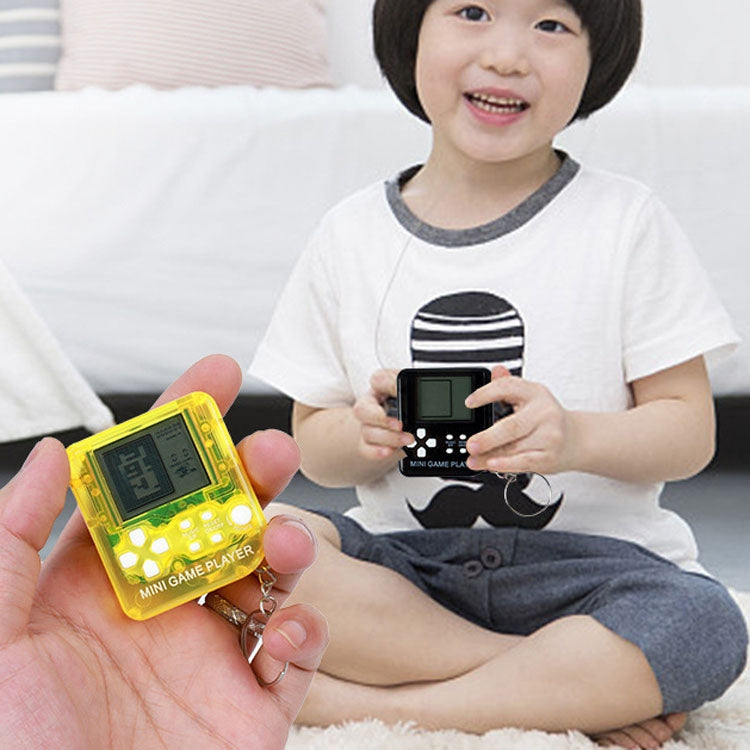 Child holding a yellow handheld mini game player keychain with small screen