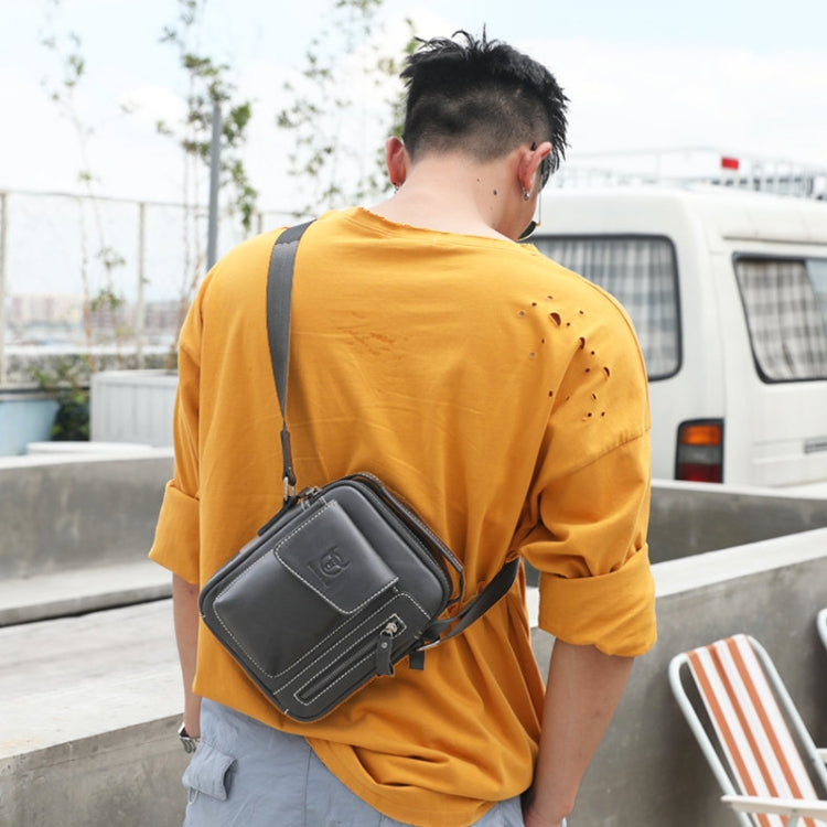 Black leather crossbody messenger bag worn by a person with adjustable shoulder strap