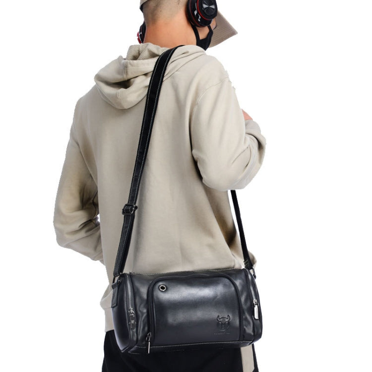 Person wearing black leather crossbody messenger bag with front zip pocket and long strap.