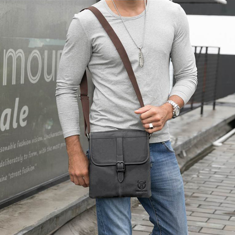 Men's dark blue leather crossbody bag worn on a person, flap front and metal buckle closure.