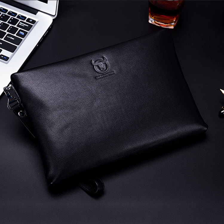 Black leather zip clutch with embossed emblem and wrist strap, flat lay.