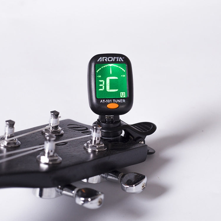 Clip-on electronic tuner attached to guitar headstock, green LED display visible