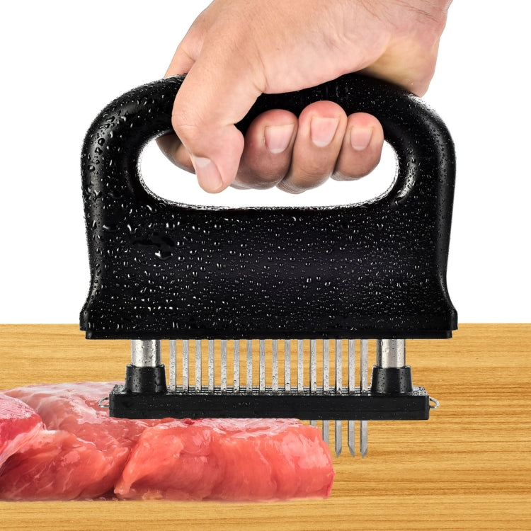 Black meat tenderizer handheld press with stainless needles over raw meat