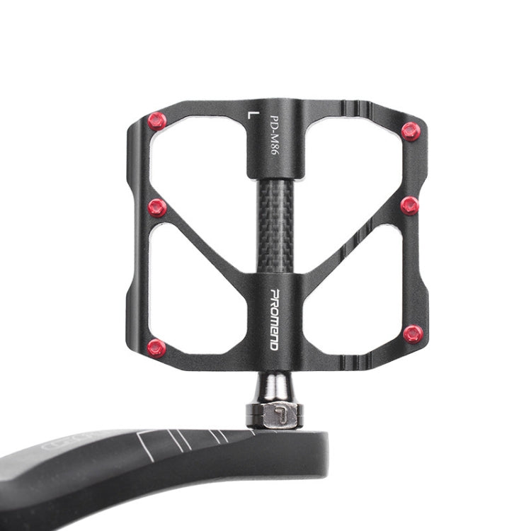 Close-up of black carbon fiber bicycle platform pedal with axles and red screws.