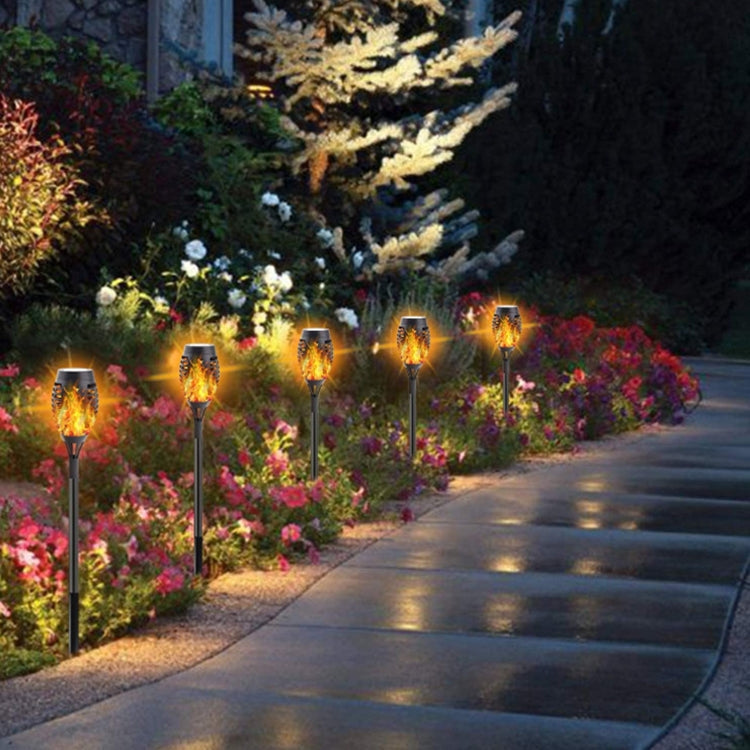 Solar flame torch lights lining a garden walkway with orange flame glow