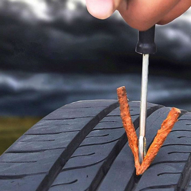 Red tire repair strip being inserted into a tire puncture