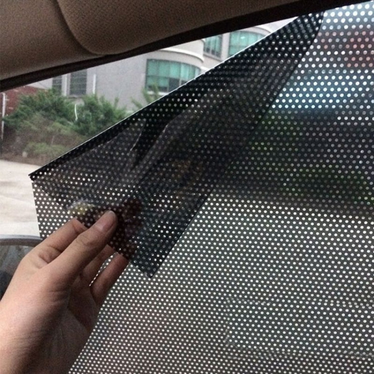 Car window sunshade film installed on glass, dot-mesh texture with partial fold