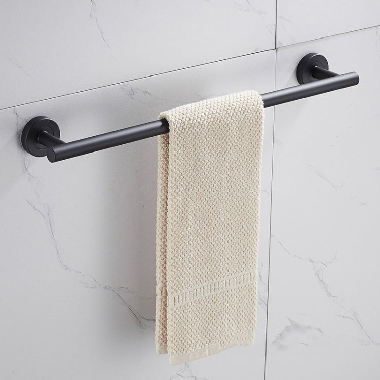 Black single towel bar with cylindrical wall mounts, holding a folded beige towel
