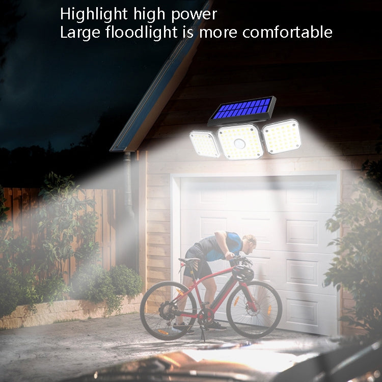Solar-powered triple-head LED wall light illuminating a garage driveway at night