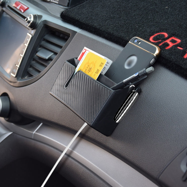 Car dashboard-mounted sticky storage box holding a phone with carbon fiber front