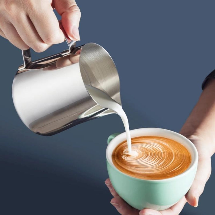 Stainless milk frothing pitcher pouring milk for latte art, with handle