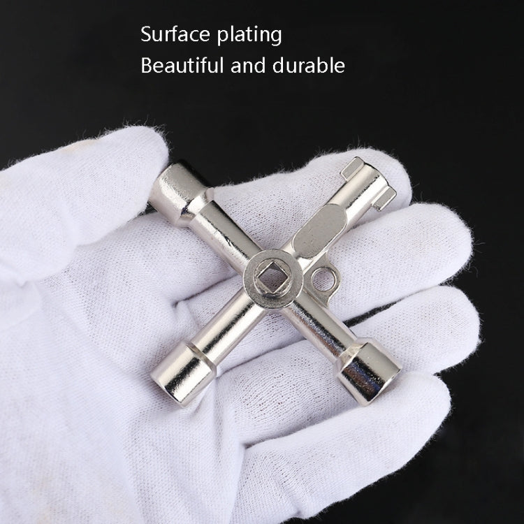 Silver cross key wrench held in white-gloved hand
