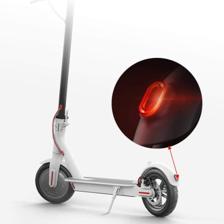 Electric scooter rear tail light glowing red on white frame