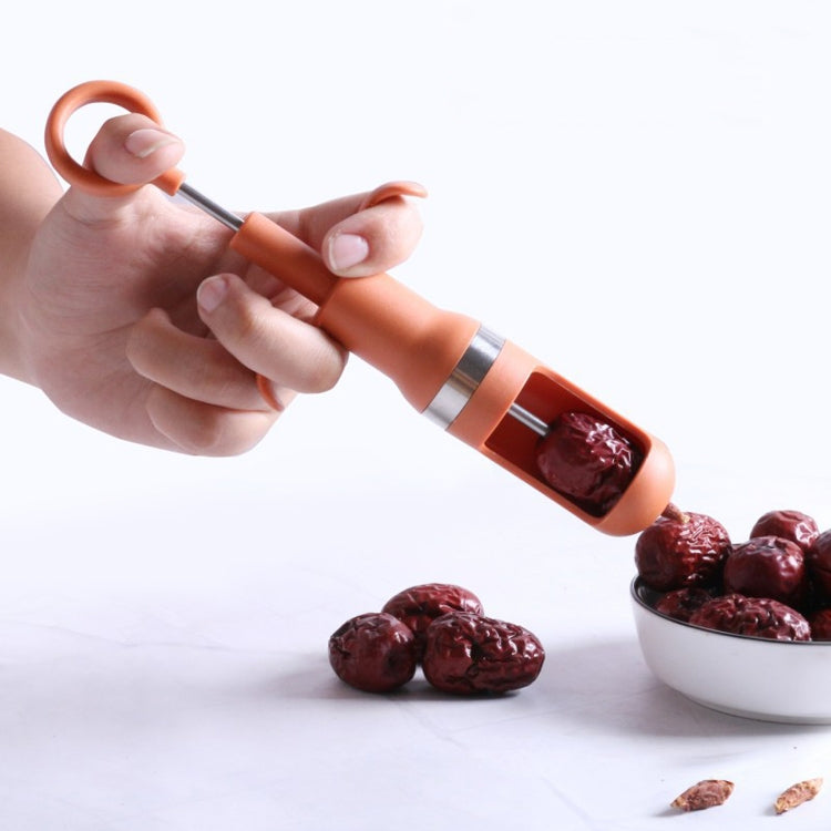 Orange date pitting device removing a pit from a date while in hand