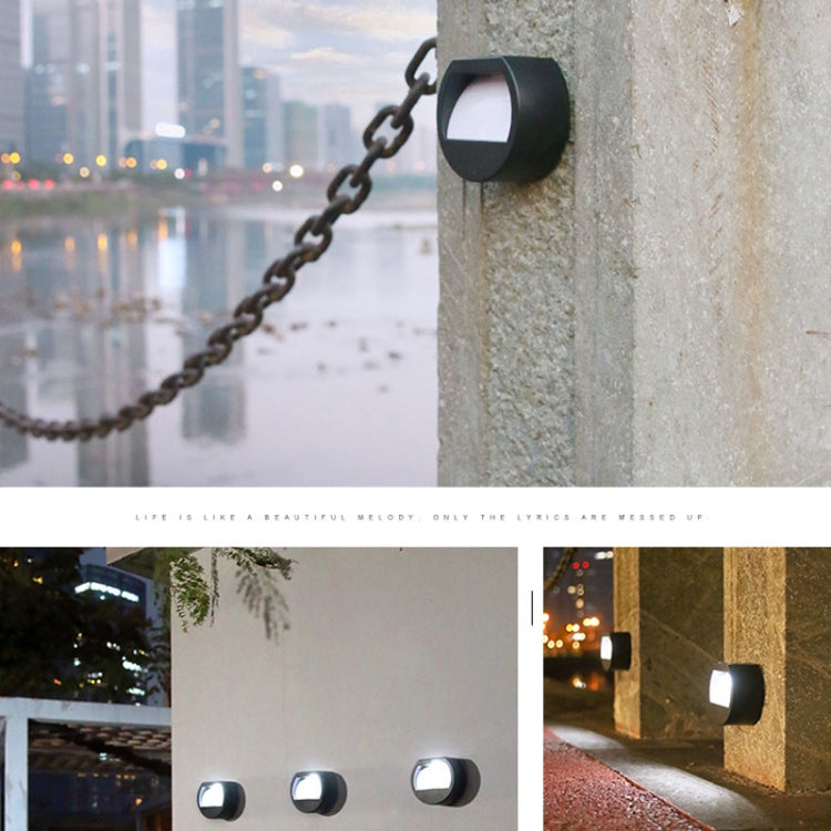 Black round solar LED wall light with frosted diffuser, mounted on chain