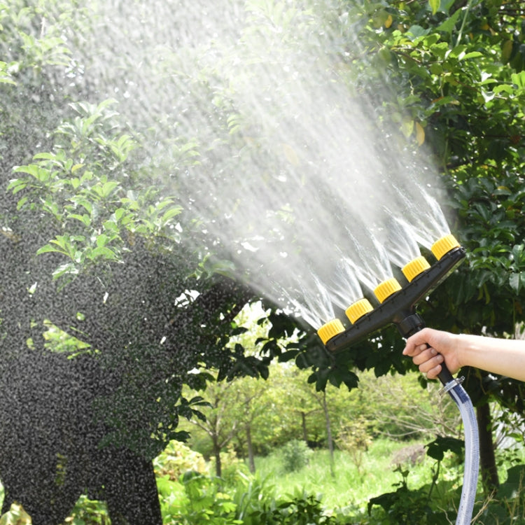 Handheld multi-head sprinkler nozzle spraying mist over garden plants