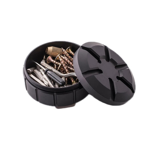 Black round first aid pill storage box, lid open showing pills and capsule tools