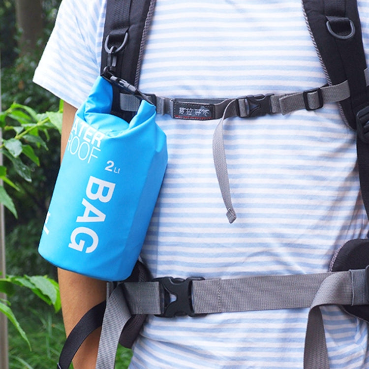Blue 2L waterproof dry bag worn on a backpack strap with buckle closure.
