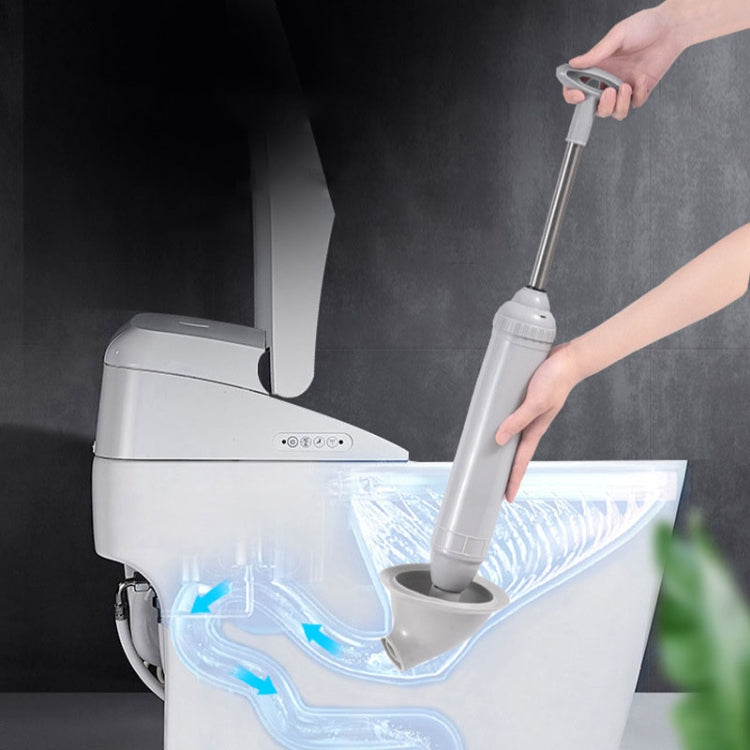 Gray handheld toilet drain vacuum using the nozzle at the toilet drain