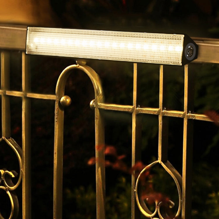 Outdoor solar LED light bar mounted on metal gate with bright warm glow