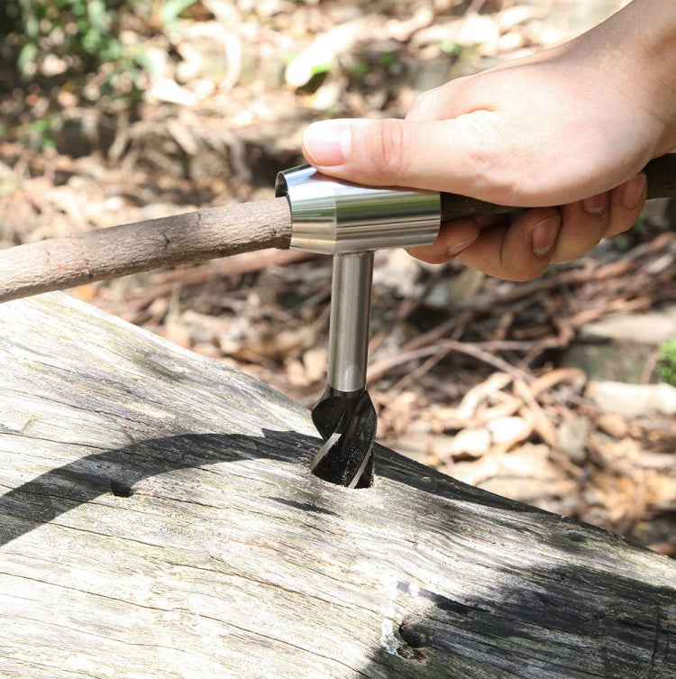 Outdoor hand screw drill punching holes in a wooden log with a metal bit