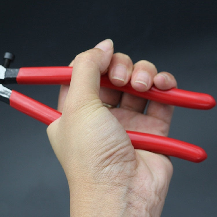 Hand holding glass tile breaker pliers with red insulated handles and metal jaws