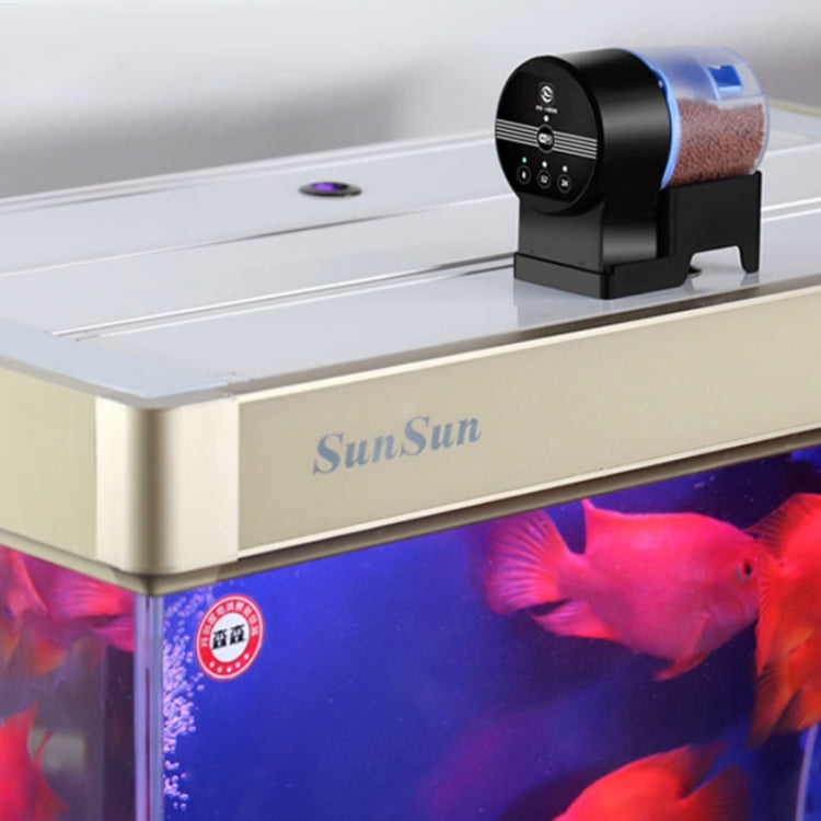 Automatic fish tank feeder mounted on aquarium top with clear hopper