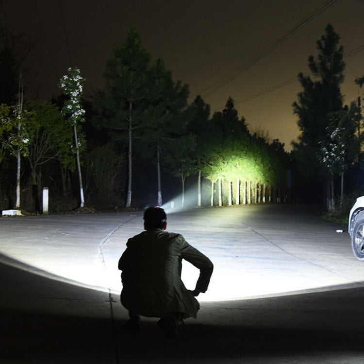 Headlamp projecting a wide white light beam on a dark path, worn by a person