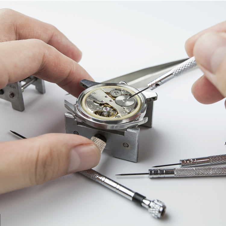 Hands using watch movement holder clamp to secure a watch movement for servicing