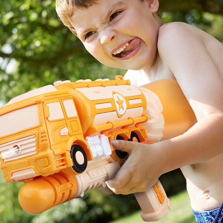 Orange plastic water pump toy vehicle held by a child outdoors