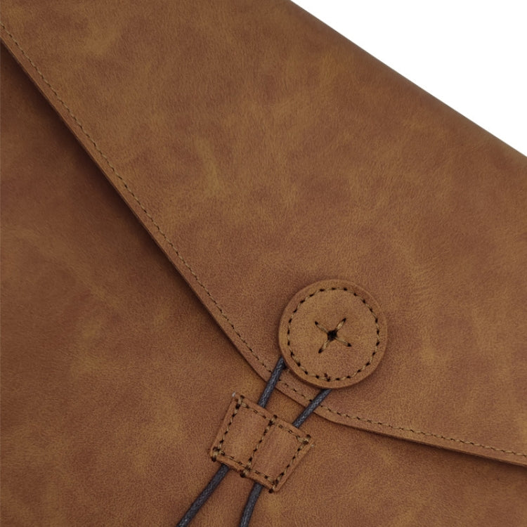 Brown leather briefcase close-up of round snap and stitched cord tab