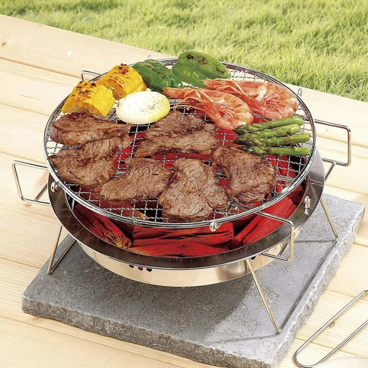 Round stainless steel barbecue grill with wire grate holding steak, shrimp, and vegetables