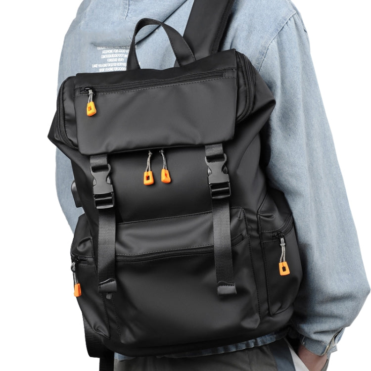 Black men's travel backpack worn on a person's shoulder with front flap pocket