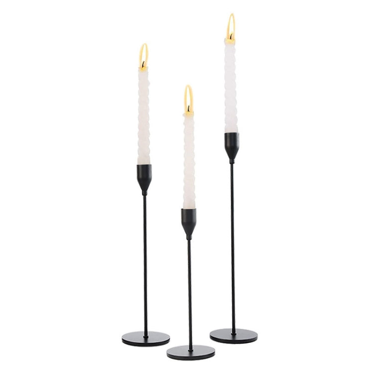 Set of three black wrought iron candle holder stands with white pillar candles