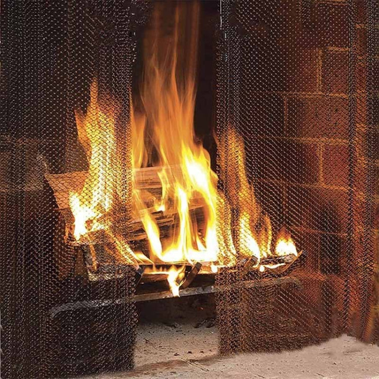 Fireplace flames viewed through black metal mesh spark screen