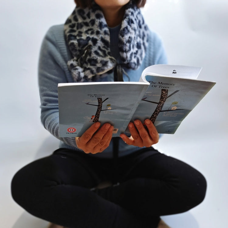 Person holding brochure while wearing a leopard-print scarf-like hot water bag cover