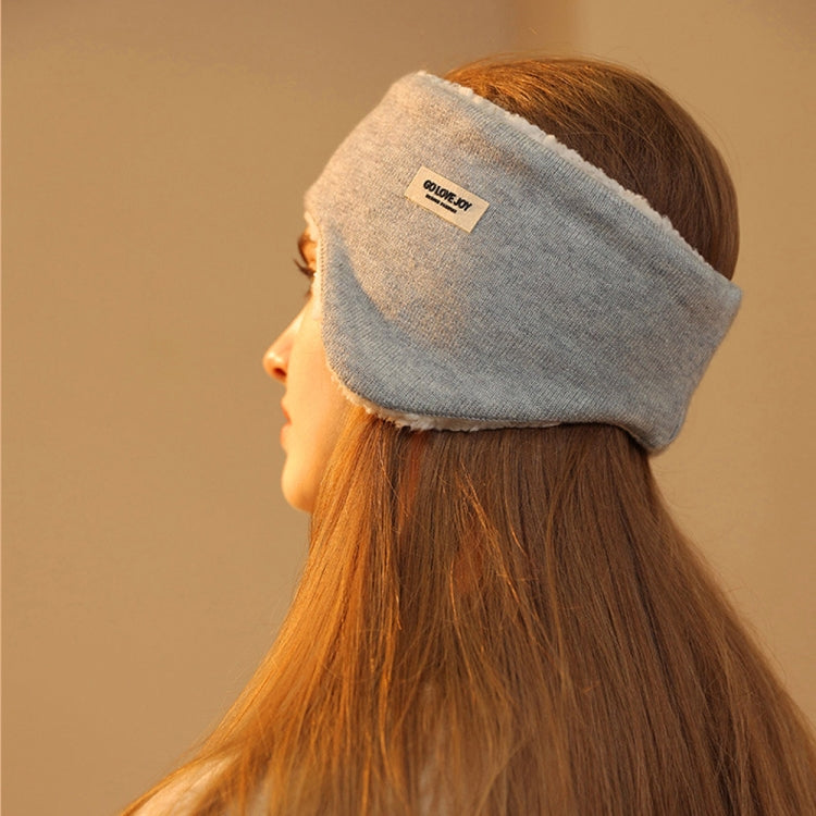 Gray sleep earmuffs worn over ears by a person in side profile