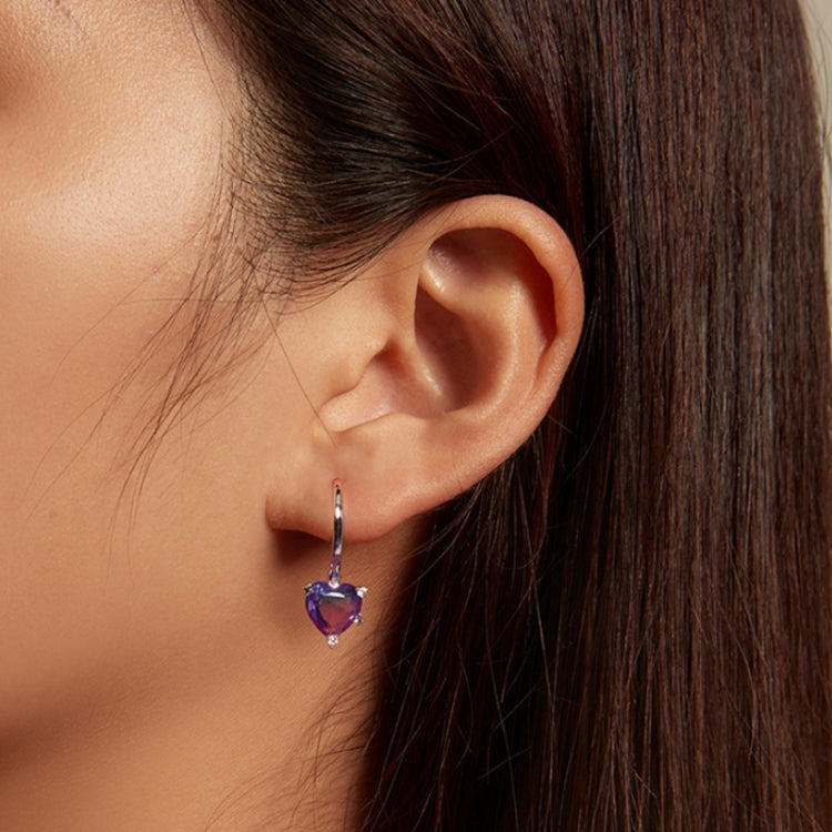Heart-shaped purple zirconia illusion drop earrings on ear with hinged hoops