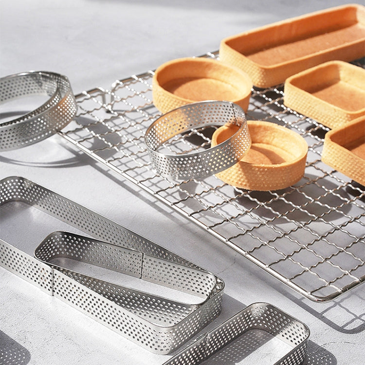 Perforated stainless steel mousse molds on cooling rack with cake bases