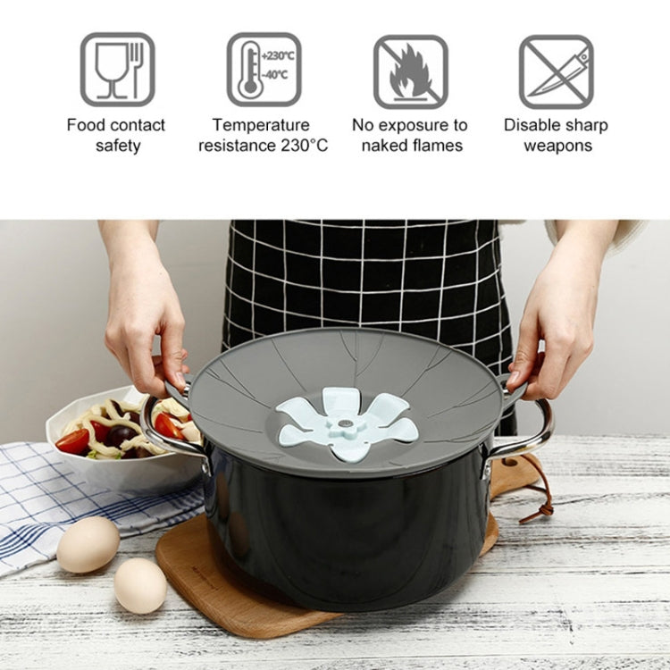 Gray silicone pot lid with white flower insert, held above a pot