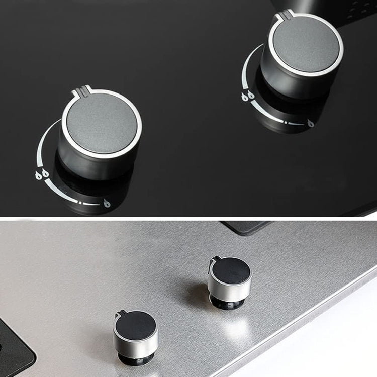 Two round metal gas stove control knobs with black tops on cooktop surface