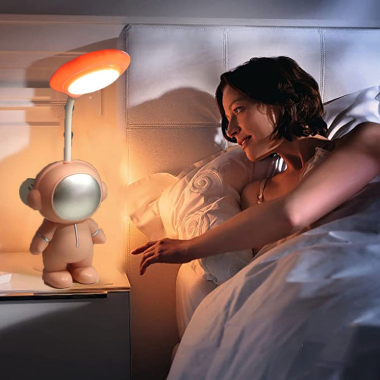 Orange astronaut LED reading lamp beside a person relaxing on a bed at night