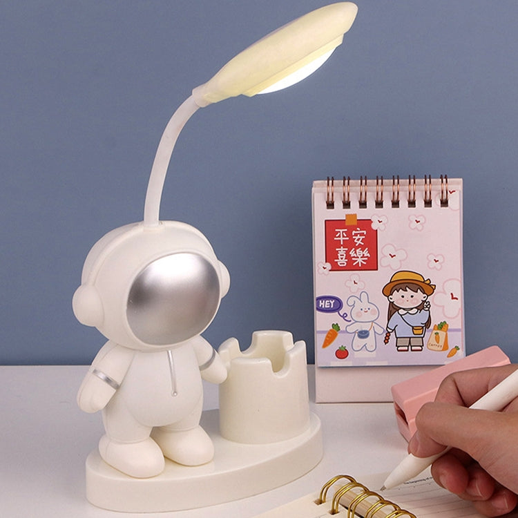 Yellow astronaut LED desk lamp with glowing lamp head and pencil holder base