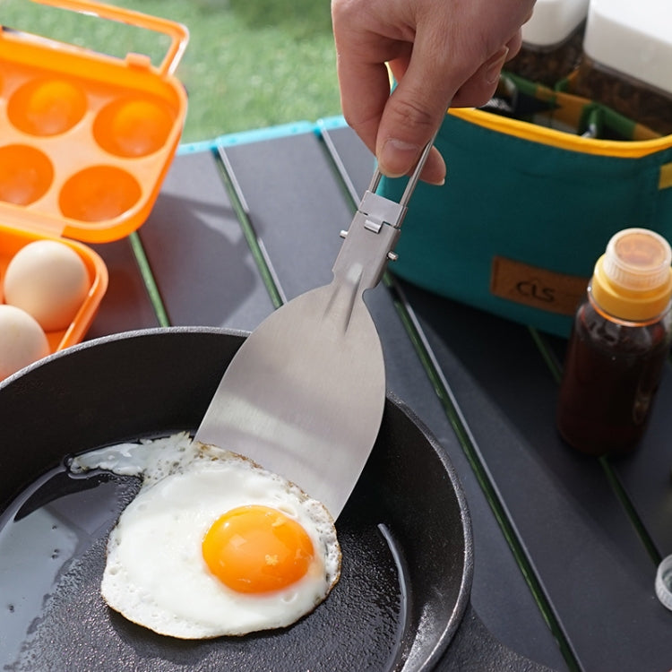 Stainless steel folding spatula flipping an egg in a frying pan