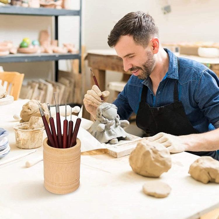 Pottery artist working with wooden trimming tools and a holder of sculpting tools.