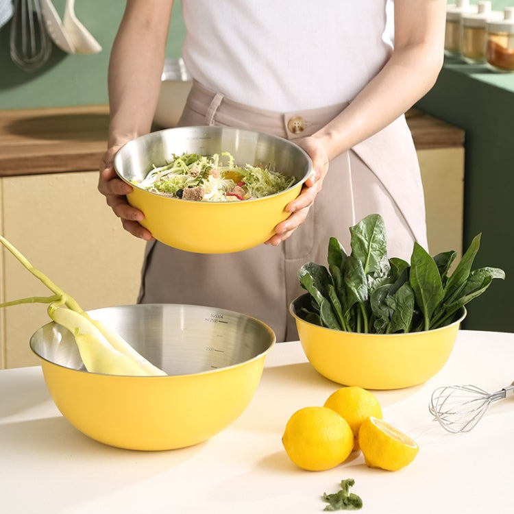 Yellow stainless mixing bowl holding salad, with another bowl and herbs on counter