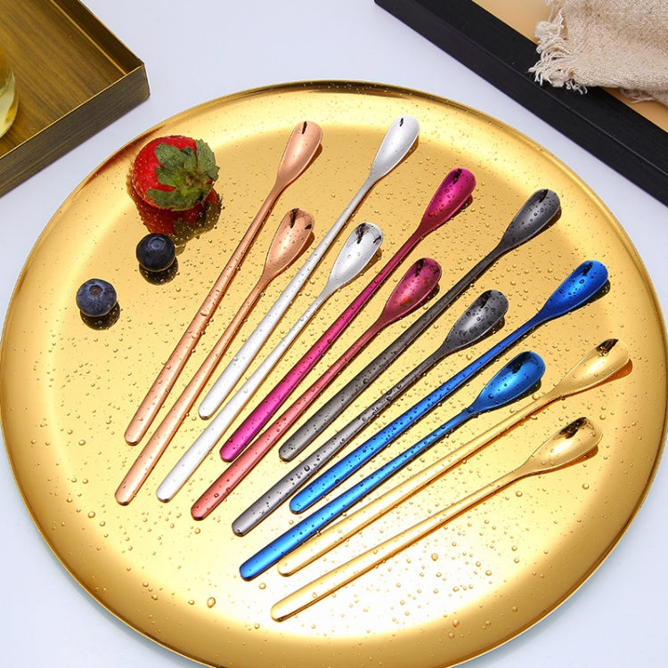 Colorful long-handled coffee spoons with square heads on round tray: pink, blue, black, gold